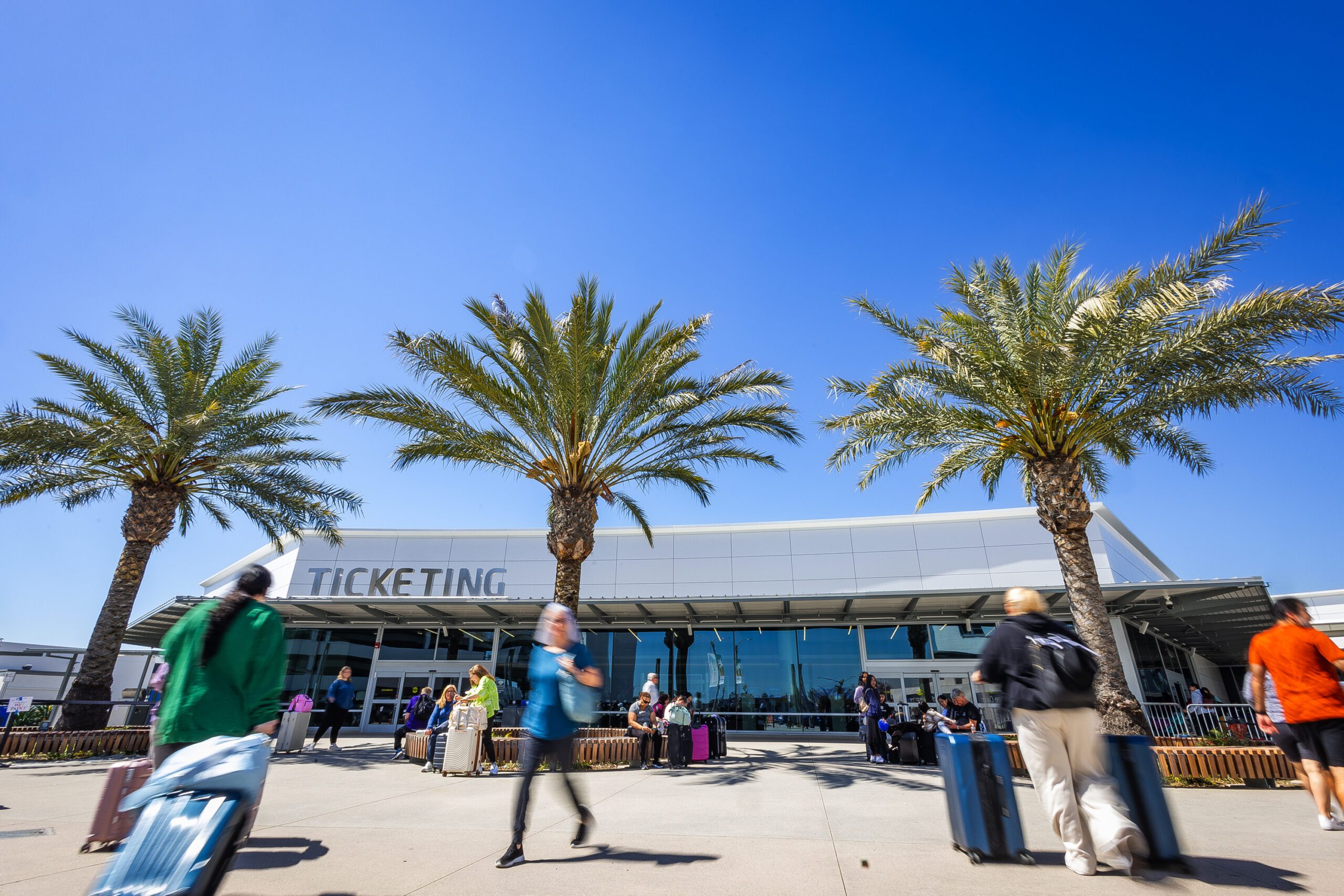 Photo of main entrance to ticketing lobby with dozens of passengers walking by.