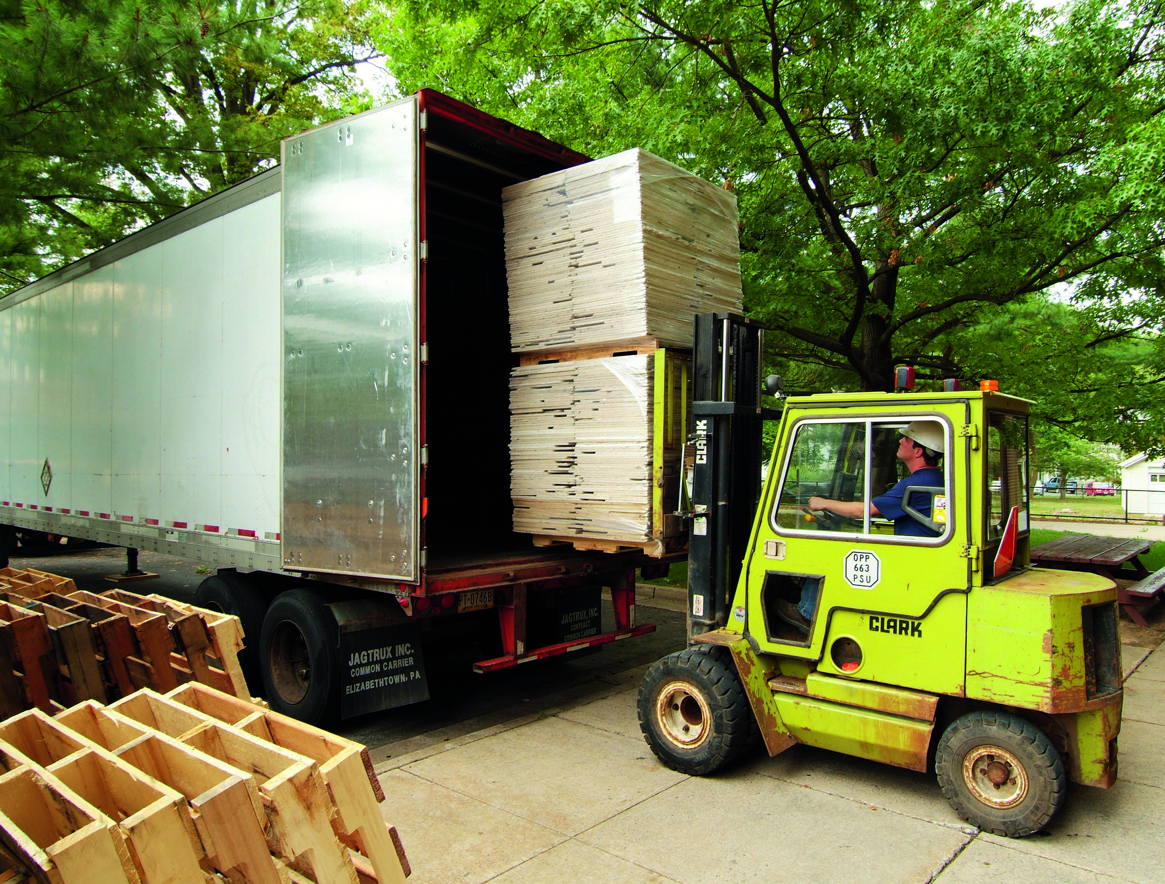 Forklift recycling paletes into the back of a cargo truck