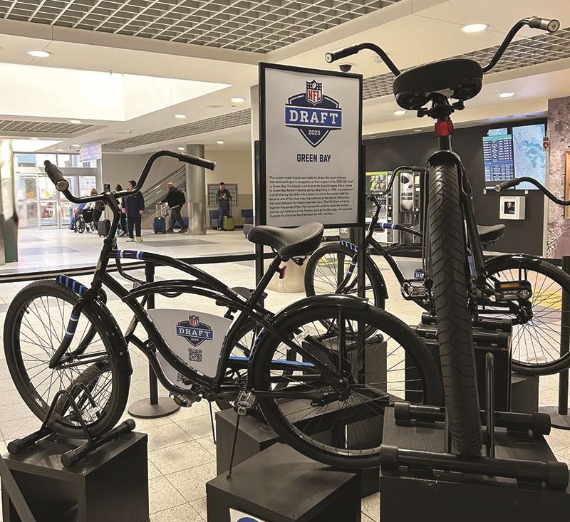 This display highlights the heartwarming tradition of Packers players riding local kids’ bikes to practice.