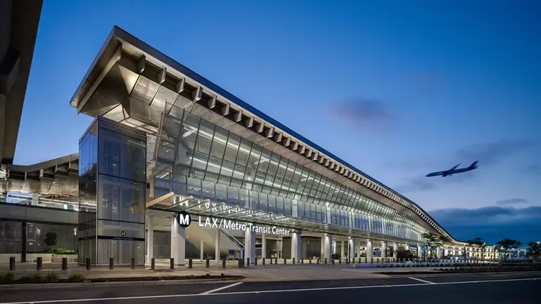 A large transit center at the airport with a plane flying by