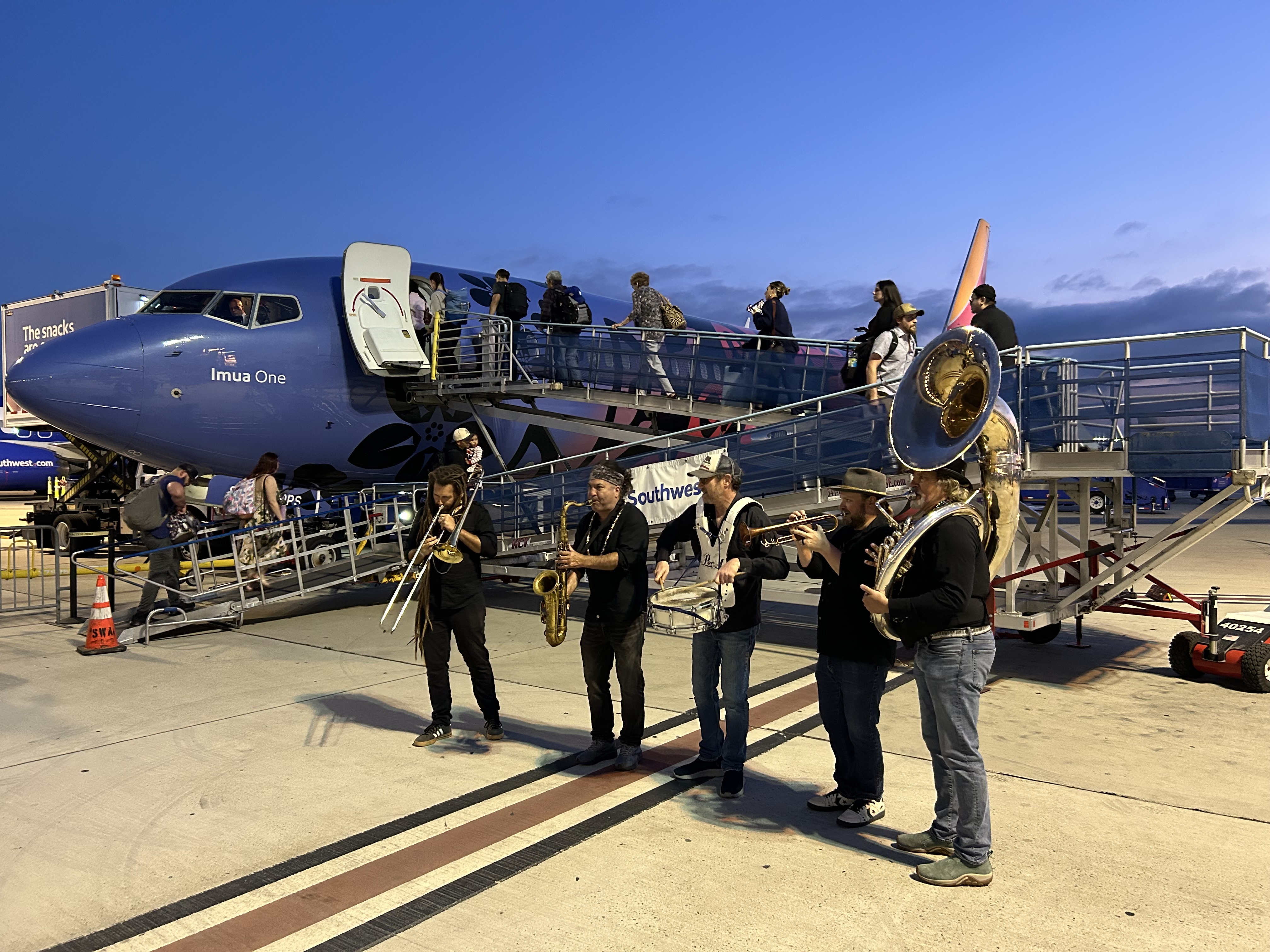 Jazz Band performs on the ramp as passengers board blue, red and gold Southwest airplane.